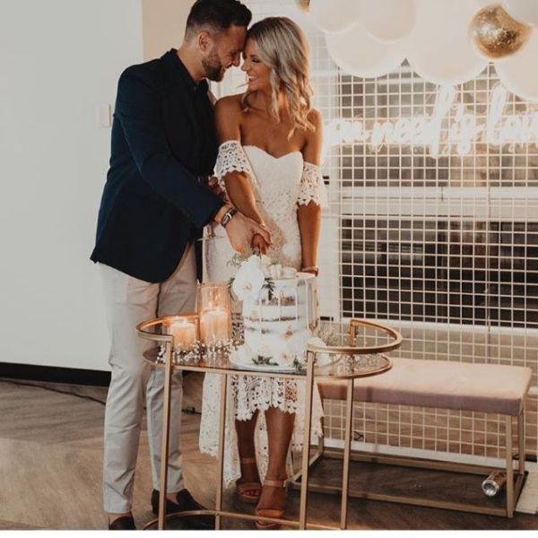 All You Need is Love white neon sign in the background as the newlyweds cut the cake - from Custom Neon