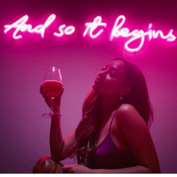 And so it begins pink LED neon light shown wall mounted behind a lady with a drink - from Custom Neon