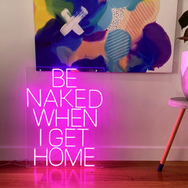 Be Naked When I Get Home LED neon sign shown on the floor beneath a painting - photo from CustomNeon.com.au