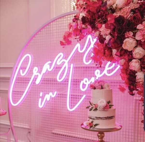 Crazy In Love Wedding Sign in brilliant LED neon flex shown in pink with wedding florals and cakes - photo from Custom Neon @customneon