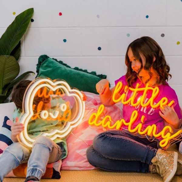 Smiley Cloud LED wall light in warm white and Little Darlings LED neon sign in orange by CUSTOM NEON®