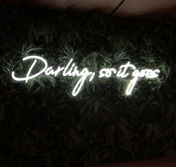 Darling, so it goes Neon Sign Quote for Weddings & Home Decor shown on green wall
 - photo from Custom Neon by Neon Collective