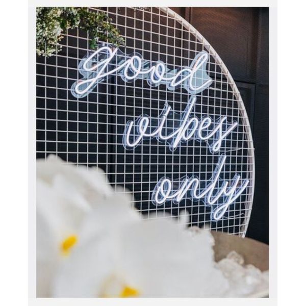 Good Vibes Only LED neon sign in 3 pieces shown on a mesh screen at an event - photo from CustomNeon.com.au