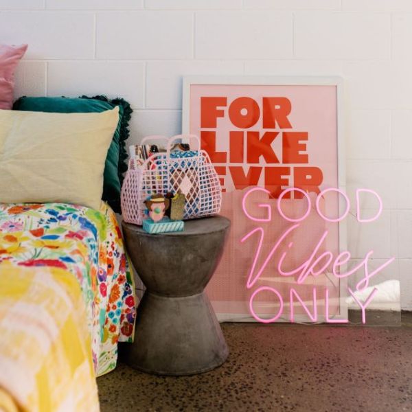 Good Vibes Only neon sign in pink with a pink jacket so it looks great both on and off - shown  in a bedroom - sign by CustomNeon.com.au