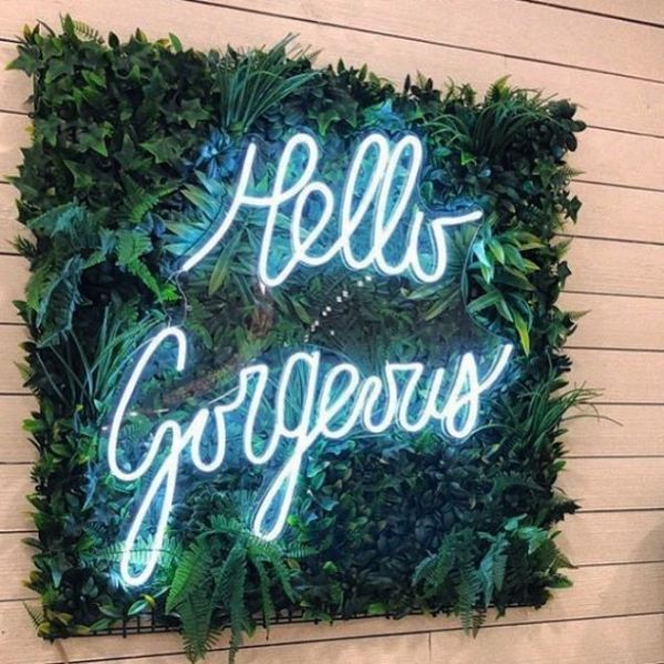 Hello Gorgeous light sign hung on a green wall in a beauty salon - Custom Neon