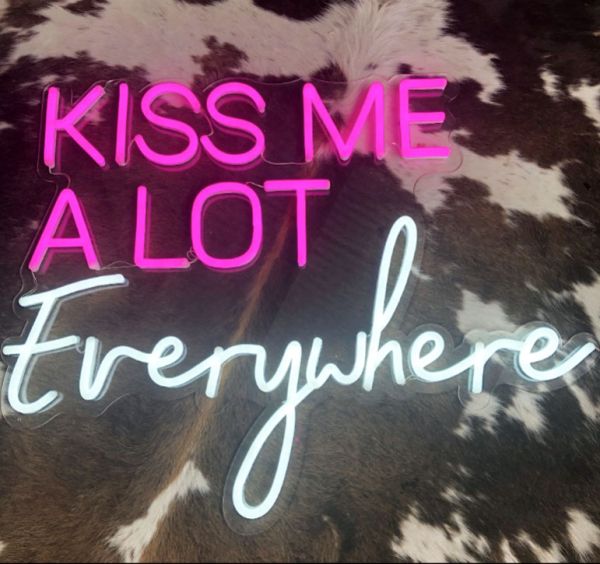 Kiss Me A Lot Everywhere LED Neon Sign in pink and white shown on faux cow hide - photo CustomNeon.com.au