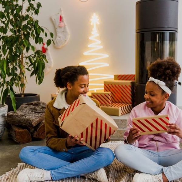 Warm white light up neon Xmas tree surrounded by Christmas stockings, a modern wood burning stove and children opening presents - by CUSTOM NEON® 