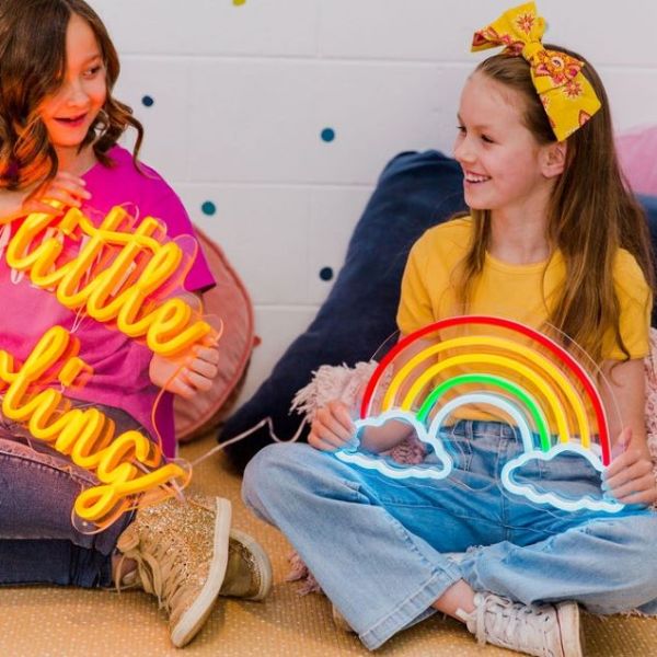 Rainbow & Clouds multi-colored Custom Neon® light held by a girl in a child's room