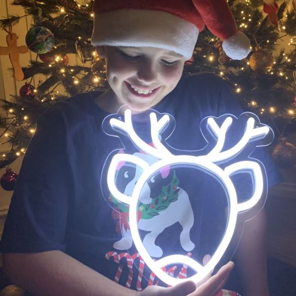 CUSTOM NEON® Reindeer light held by a child with a Christmas decorations in the background