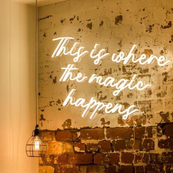 This is Where the Magic Happens faux neon sign in warm white on distressed brick wall @customneon