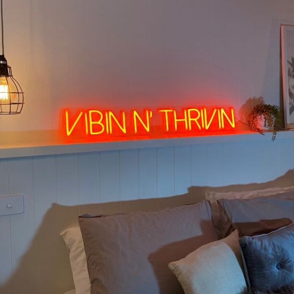 Vibin 'n Thrivin red neon flex sign shown above a bed - from Custom Neon