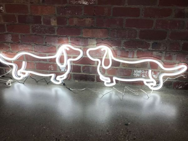 Two sausage dog neon lights shown nose to nose in front of an exposed brick wall - from Custom Neon by Neon Collective