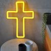 LED neon cross shown illuminated in yellow, on a side table - from Custom Neon by Neon Collective