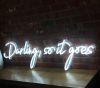 Beautiful cursive neon word sign * Darling, so it goes * shown against exposed brick wall
 - photo from Custom Neon by Neon Collective