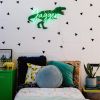 Personalised LED neon child's name sign with dinosaur background shown in child's bedroom- from Custom Neon by Neon Collective