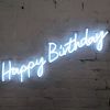 * Happy Birthday * is a lightweight, portable neon sign in modern cursive font, shown against a brick wall - photo from Custom Neon by Neon Collective
