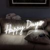Happy Days LED neon sign shown illuminated on a couch - photo CustomNeon.com.au