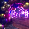 Let's Party portable LED neon sign shown on a wire mesh background surrounded by balloons - from Custom Neon® @customneon