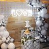 LOVE with a heart LED neon sign surrounded by wedding decorations - photo from Custom Neon by Neon Collective