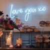 Love You XO LED neon light shown wall mounted behind the sweets table at an event - from CustomNeon.com.au