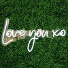 Love You XO LED neon light shown on a green wall - from Custom Neon by Neon Collective