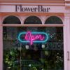 LED Neon Flex open sign in a modern cursive font surrounded by an oblong frame shown in a florist's shop window - from CustomNeon.com.au