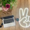 LED Neon Peace Sign Light shown on wooden floor - Photo Custom Neon by Neon Collective