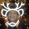 CUSTOM NEON® Reindeer white light sign held by a child with a Christmas tree in the background