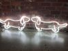 Two sausage dog neon lights shown nose to nose in front of an exposed brick wall - from Custom Neon by Neon Collective