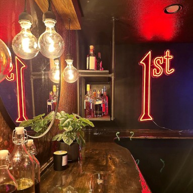 Red Custom Neon® 1st sign on a dark wooden wall in the bar area of a sunken theatre room