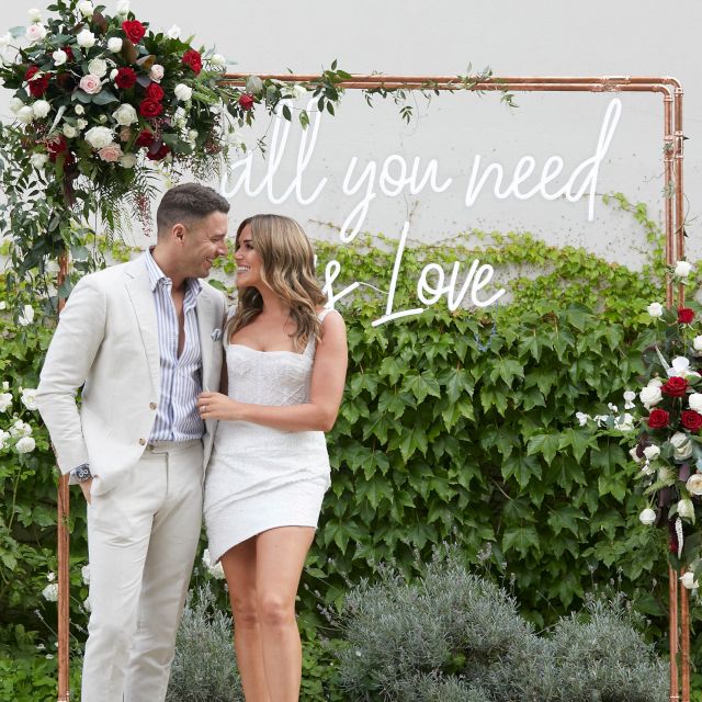 All You Need is Love white outdoor Custom Neon® sign attached to a frame as a selfie backdrop @georgiealove @leeroyelliot