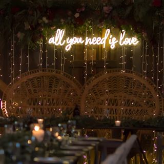 Custom Neon® warm white All You Need is Love sign behind the top table