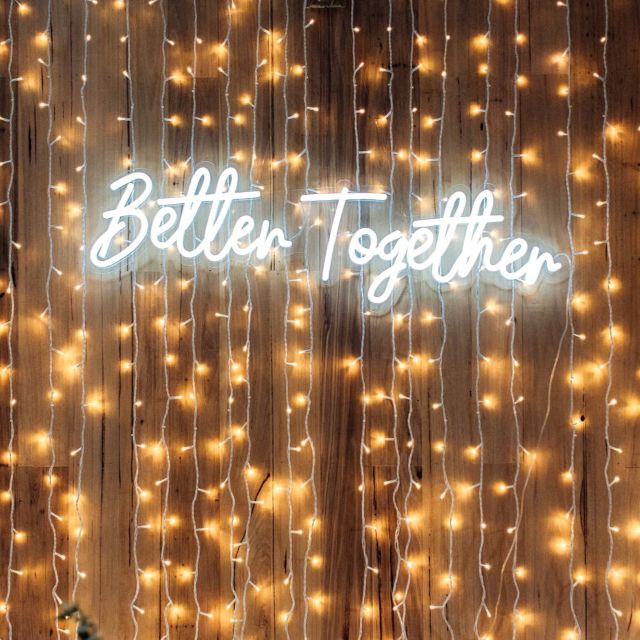 Custom Neon® warm white Better Together sign with string lights for a wedding photo backdrop