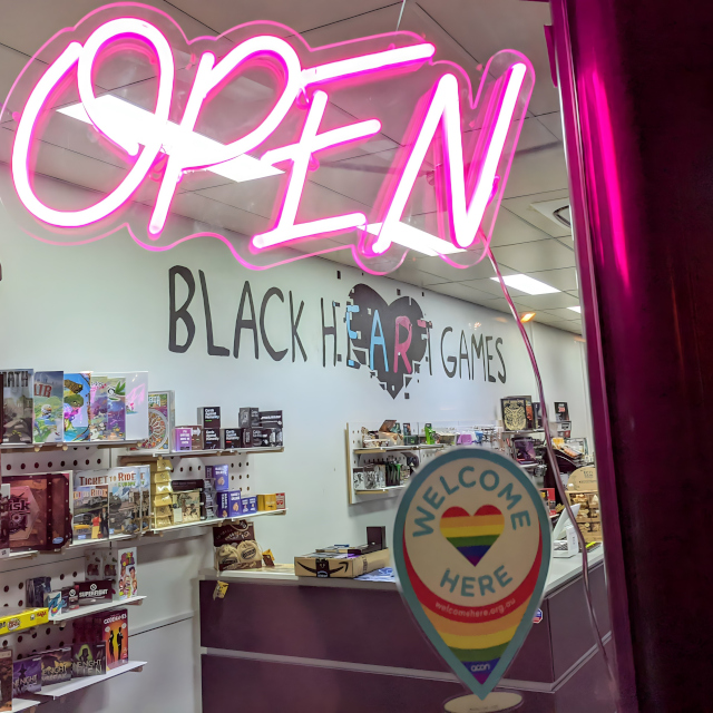 Custom Neon® pink open sign in the storefront window @blackheartgames_2350