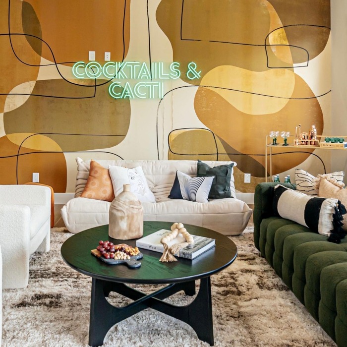 Cocktails and Cacti double lined green LED Custom Neon® sign on a boulder mural wall overlooking a South Wesern inspired living room in an Airbnb designed by Somerled