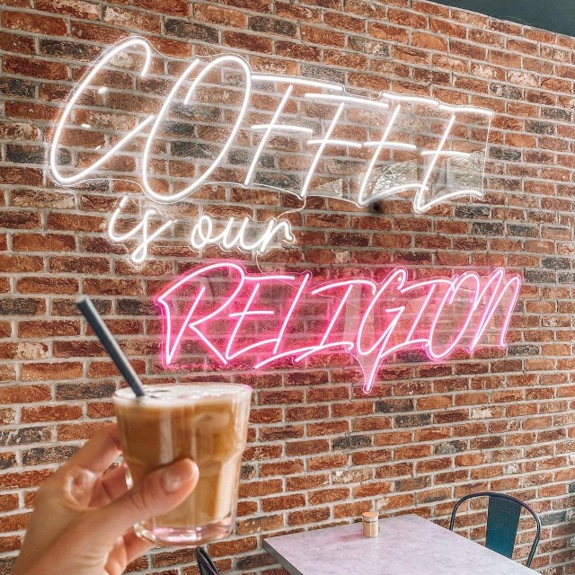 Coffee is our religion large Custom Neon® sign on a brick wall