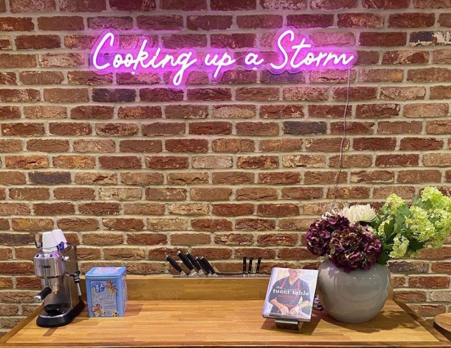 Custom Neon® pink Cooking Up a Storm kitchen sign on brown brick wall @martin.whitehouse.life