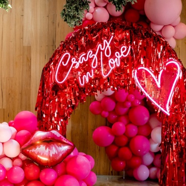 Custom Neon® heart and Crazy In Love sign on streamer arch with balloon garlands