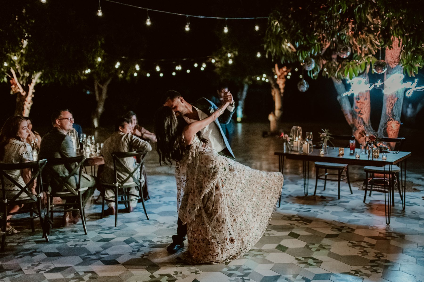 White Custom Neon® newlywed name signs hung from a tree during an outdoor wedding party