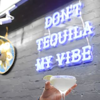 Don't Tequila My Vibe Custom Neon® sign on a light grey brick wall @lacabramexican