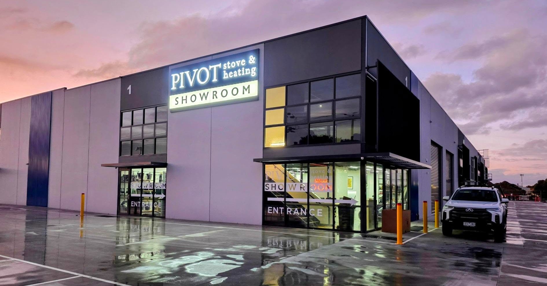 Pivot Stove & Heating front lit white LED channel letter sign made by Custom Neon®, shown on the exterior of a large building in front of a sunset