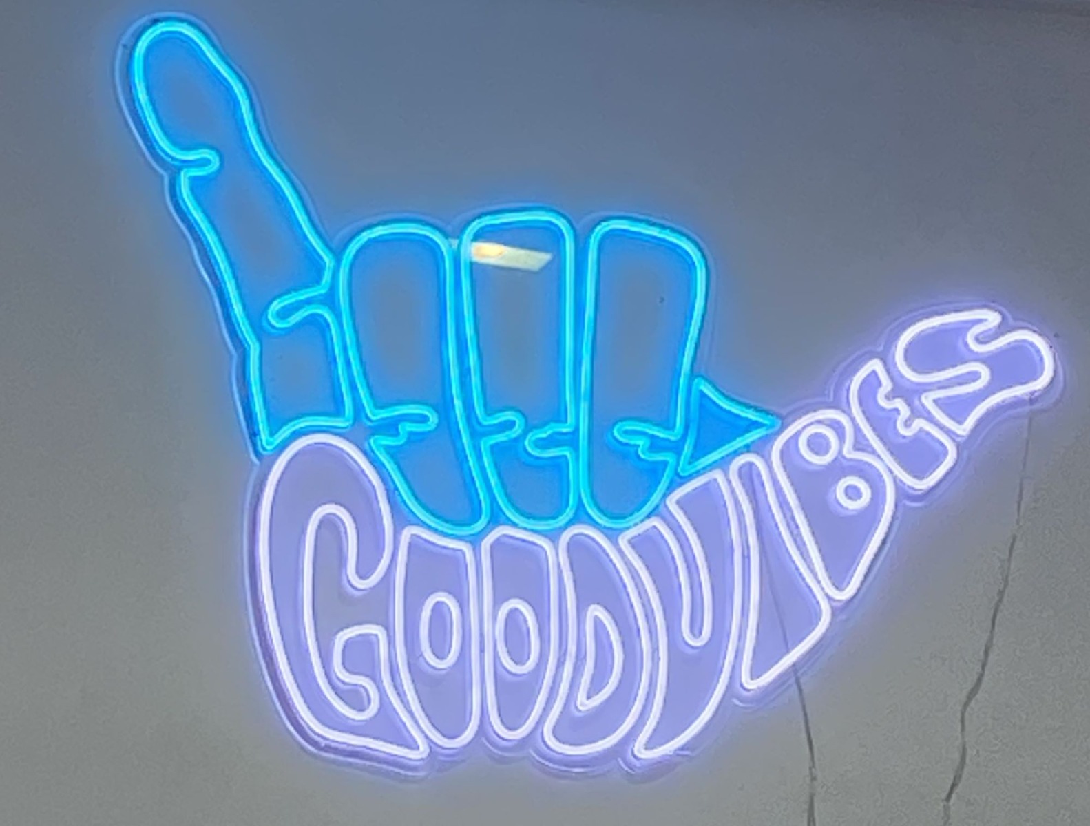 Good Vibes shaka hand artwork by Custom Neon® mounted on a  white wall @theresidentbarber