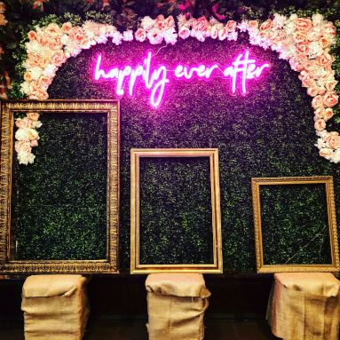 Happily Ever After pink Custom Neon® sign above 3 empty photo frames making up a wedding photo booth