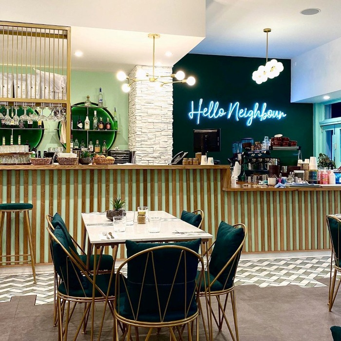 Hello Neighbour white Custom Neon® sign on a dark wall in a cafe @helloartusi_gnoccheria