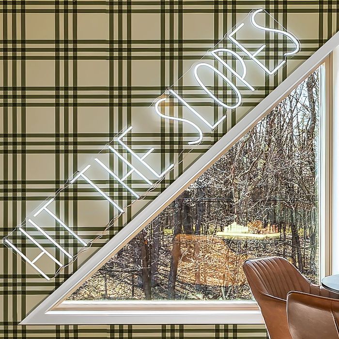 Hit the Slopes white LED Custom Neon® sign above a triangular window in an Airbnb cabin designed by Somerled