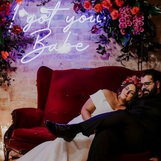 I got you babe Custom Neon® lyric sign in pink hung from a frame surrounded by roses