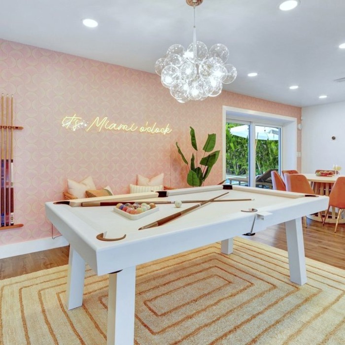 It's Miami O'clock orange LED Custom Neon® sign on pink patterned wallpaper in a vacation villa designed by Somerled