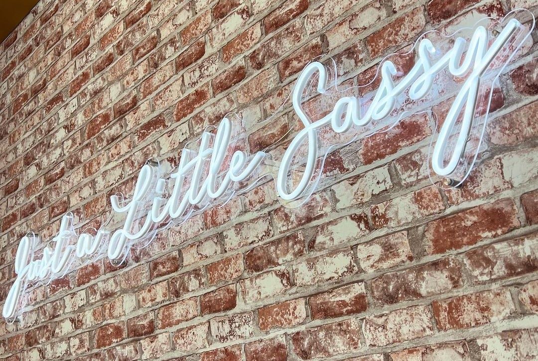 Just a Little Sassy white Custom Neon® sign on a brick wall