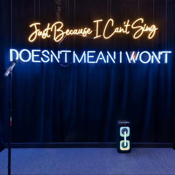 Just Because I Can't Sing Doesn't Mean I Won't LED Custom Neon® stage backdrop in two colors and fonts with microphones in the foreground of a karaoke room designed by Somerled