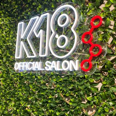 White Custom Neon® K18 logo sign on greenwall @k18